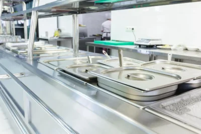 Imagem de um balcão térmico quente para self service, ideal para manter a temperatura dos alimentos em ambientes comerciais. Estrutura de metal com recipientes para alimentos.