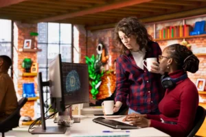 Duas profissionais de marketing discutindo estratégias de uso de ferramentas de IA em um ambiente de escritório moderno, promovendo inovação em 2025.