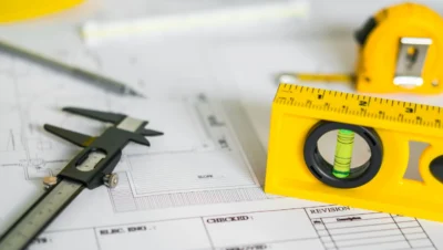 Ferramentas de medição, como régua e compassos, sobre projetos técnicos, exemplificando os fatores essenciais na avaliação de materiais para projetos de longa duração.