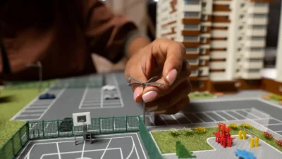 Detalhe de uma maquete de um edifício com foco em infraestrutura e acessibilidade, representando conceitos de modernização predial, gestão digital, mobilidade inclusiva e proteção estrutural.